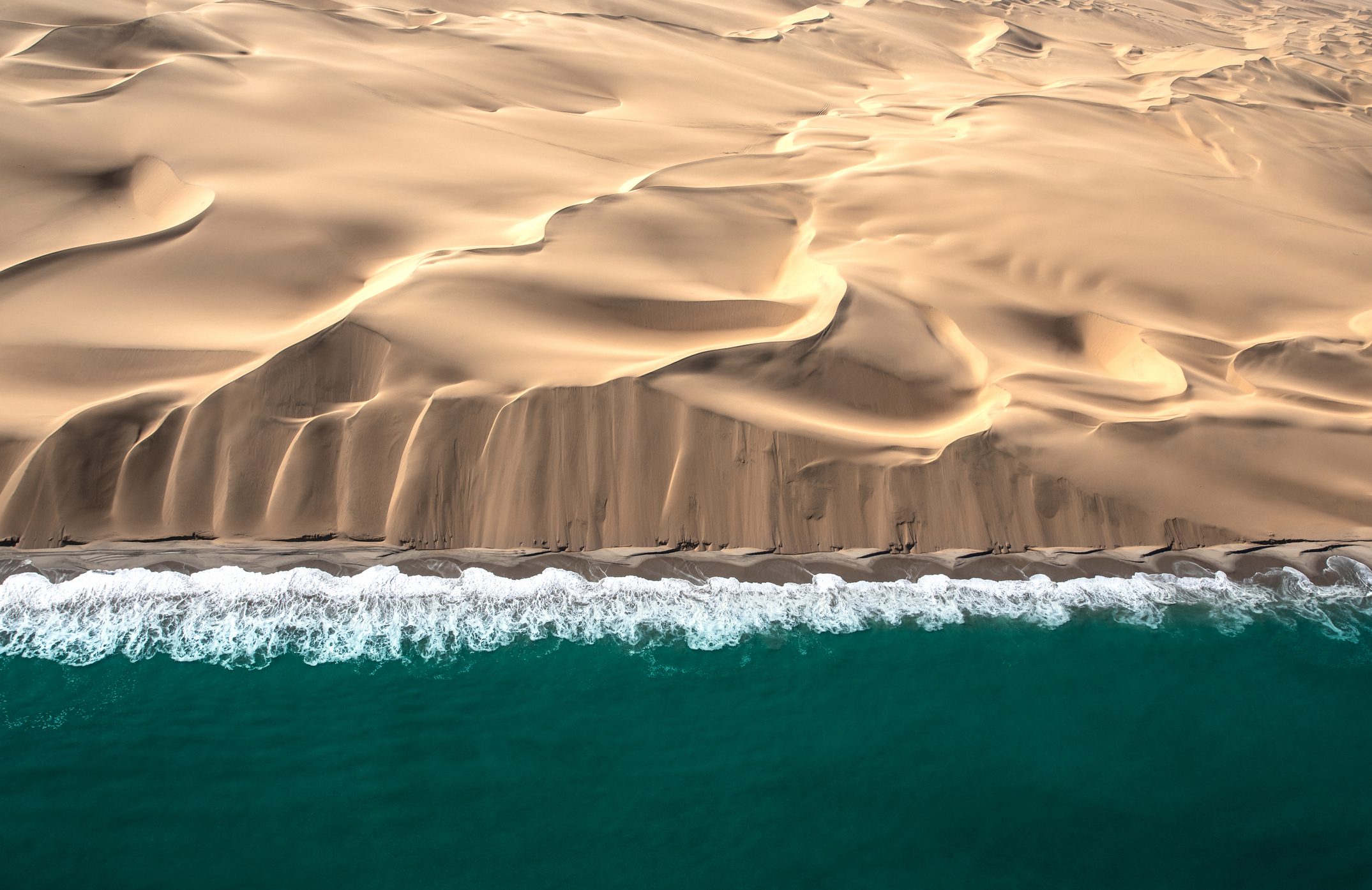 Aerial view of Skeleton coast dunes meeting Atlanic ocean.